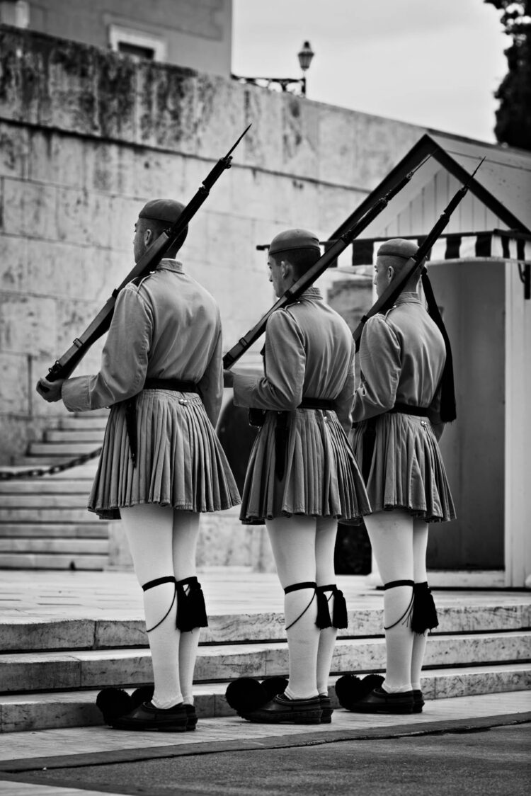 “Solenes” - Três Evzones solenemente detêm-se por alguns instantes diante do Parlamento Helênico em frente à Tumba do Soldado Desconhecido. Parlamento Helênico, Atenas, Grécia.