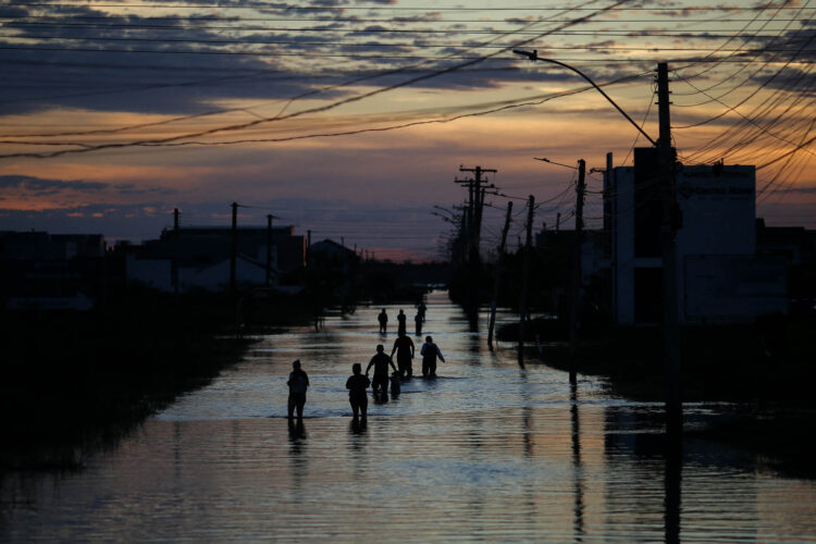 Após leve baixa no nível das águas, diversas pessoas são vistas caminhando por ruas alagadas no centro de Eldorado do Sul. Foto: Anselmo Cunha/AFP