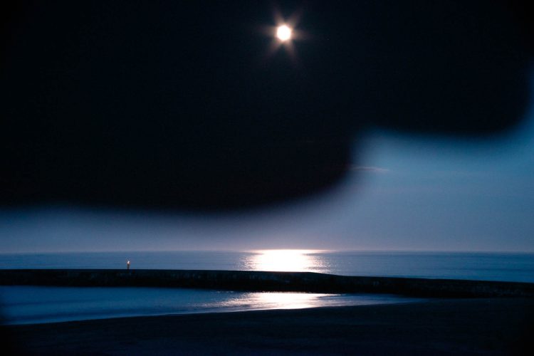 Moonlight
I once asked a friend who works in radioactive decontamination, “What do you do when you have free time?”
He said, “I go to the sea and watch the moon.”
One night, I photographed a full moon.
But I mishandled the camera, and the result looked as if day and night existed at the same time.
I laughed at the surreal image, while he, who prefers simple and grounded scenery, remained quiet.
Having lived through the disaster of 2011 and now facing danger each day in his work, he seemed tired of fiction.