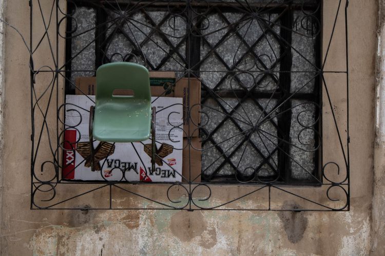 "Vendedor"
La silla verde, pequeña y ligera, cuelga de la reja como un objeto olvidado, pero no lo está. Pareciera que es el puesto fijo de alguien que no tiene lugar ni vitrina. Desde allí, entre las rendijas del hierro, esta persona ve la vida pasar mientras nos vende unos sorbetos "Mega", de colores chillones, sabor conocido y promesas sencillas.