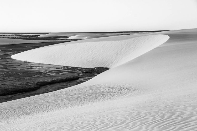 Dunas com marcas feitas pelo vento e lagoa semi seca.