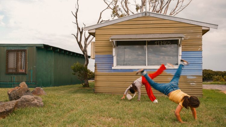 Children cartwheeling outside a house. Home as a place of safety, freedom and childhood.